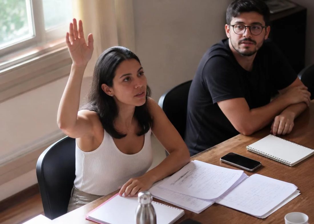 Dupla preparando a rodada seguinte, com caderno aberto e canetas coloridas na mesa